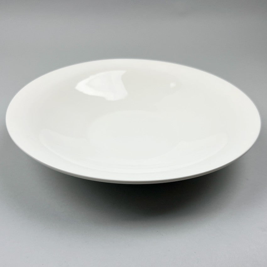 White ceramic shallow bowl with a deep pasta plate on a gray background, shot from the top. with angle