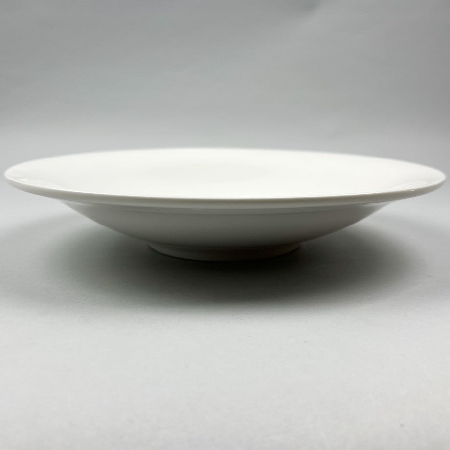 White ceramic shallow bowl with a deep pasta plate on a gray background, shot from the side.